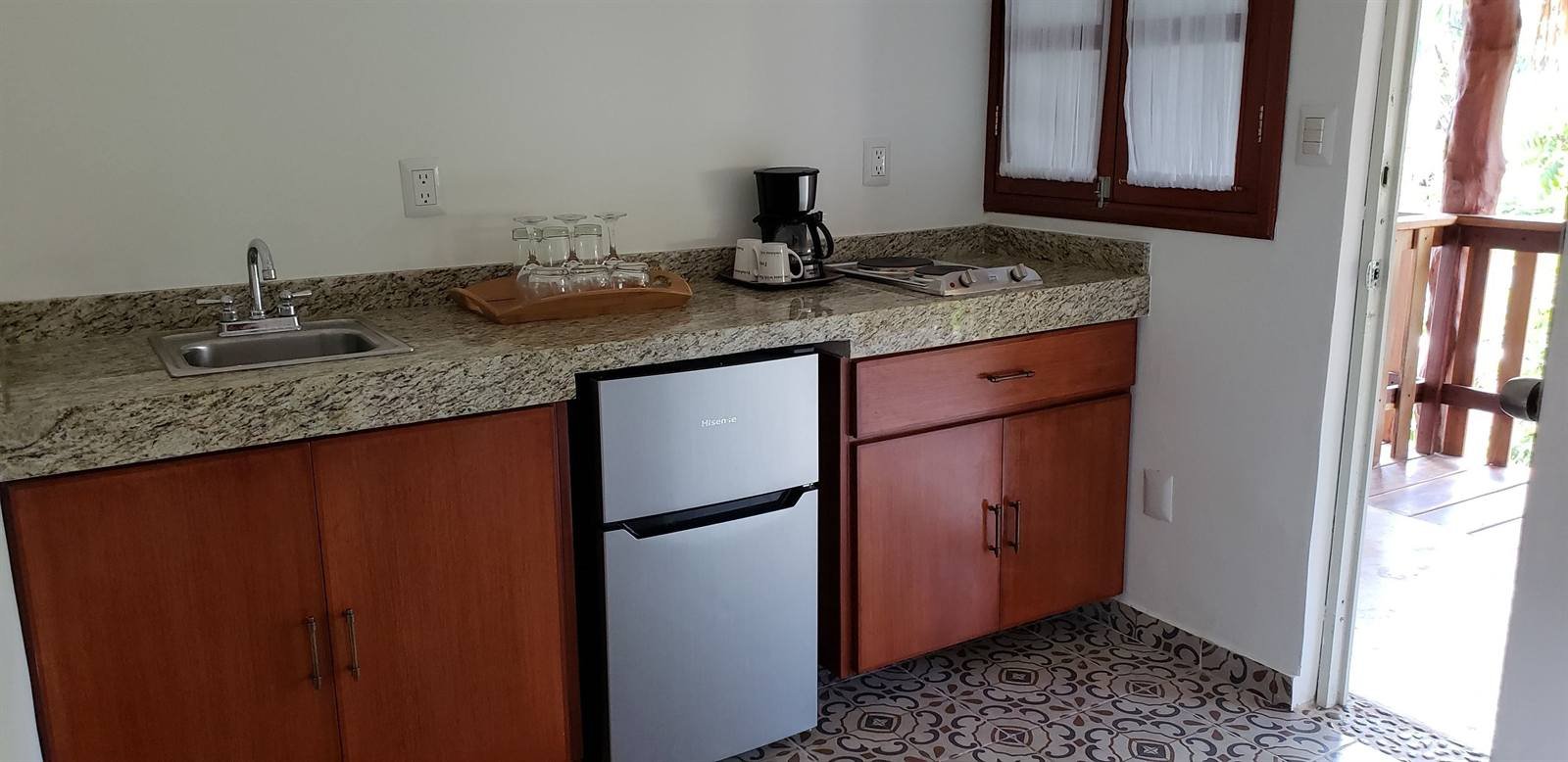 Kitchenette with a granite counter, sink, small fridge and coffee maker